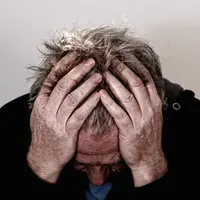 homme se tenant la tête entre les mains