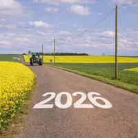 Tracteur sur une route de campagne entourée de champs de colza avec l’inscription 2026 sur la route.