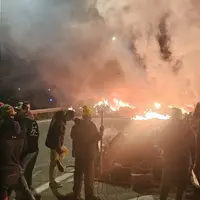 Blocage d'une voie d'autoroute le soir par des agriculteurs de la Coordination rurale, avec des pneus enflammés, des palettes de bois et des ballots d