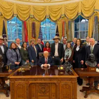 donald trump entouré de plusieurs personnes dans le bureau ovale