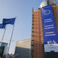 Le bâtiment de la Commission européenne à Bruxelles vu de l'extérieur, avec des drapeaux européens.
