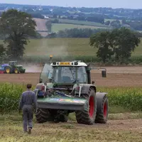 Agriculteur derrière son tracteur devant un champ de maïs
