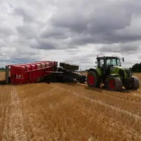 Accident de benne lors de la vidange, benne renversée sur un terrain agricole à côté d'un tracteur.