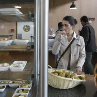 Etudiante avec son plateau dans une cantine scolaire en réflexion sur son menu, devant des fruits et des entrées.