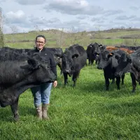 L'éleveuse Mathilde Deramond dans une prairie de son exploitation en Ariège avec ses bovins allaitants, des Limousins et des Angus