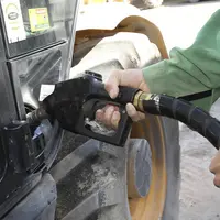 agriculteur tenant un pistolet pour faire le plein de son tracteur