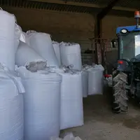 des sacs d'engrais et un tracteur entreposés dans un hangar agricole