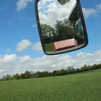 Champ de blé depuis la cabine d'un tracteur avec le rétroviseur visible.