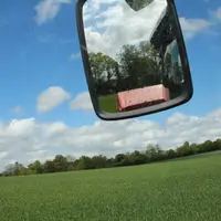 Culture de blé vue depuis la cabine d'un tracteur, avec le rétroviseur visible.