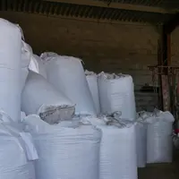 Stock d'engrais sous un hangar agricole, avec le tracteur.