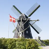 drapeau planté dans un champ devant un moulin