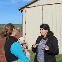 deux femmes qui discutent dont une tient un petit mouton dans les bras