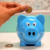 Tirelire bleue dans laquelle une main dépose une pièce de monnaie..