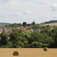 paysage rural avec champ et bottes de paille au premier plan et village en arrière plan