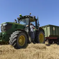 Jeune femme de dos en train de monter sur un tracteur dans un champ