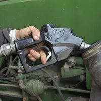 Main sur un pistolet de carburant au-dessus du réservoir d’un tracteur.