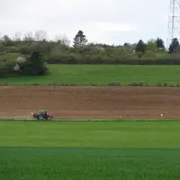 Paysage de zone intermédiaire au printemps, avec un tracteur dans un champ.
