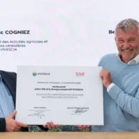 deux hommes assis montrent à l'objectidf un document