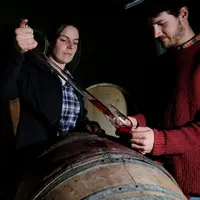 Vigneronne et vigneron goutant leur vin rouge élevé en fut de chêne dans leur chai avant assemblage de la cuve. gouter. Vigne. Vin. Viticole.