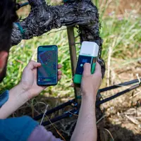 Opérateur géolocalisant un cep de vigne à l'aide de son application sur smartphone connecté à un boîtier de réception RTK