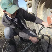 vérification de la pression des pneus d'un tracteur avec un manomètre. Agriculteur. contrôle du matériel. machinisme agri
