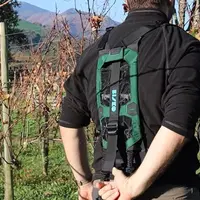 Opérateur dans les vignes réglant la tension d'un exosquelette Bisko