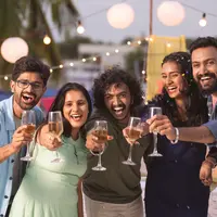 Group of youthful Friends saying happy new year by holding champagne glassless during 2024 party celebration - concept of frie