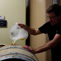Salarie d une exploitation viticole de Champagne mettant a niveau le remplissage de futs de chene avec le jus de la cuvee dura