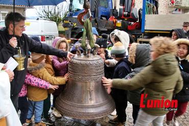 Des enfants touchent de leur main une grosse cloche de bronze. 