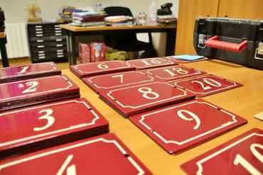 Des plaques de numéro étalées sur un bureau en vue de l'adressage.