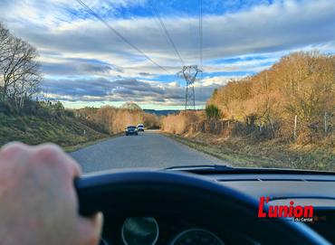 Main sur le volant d'un véhicule sur une route départementale. 