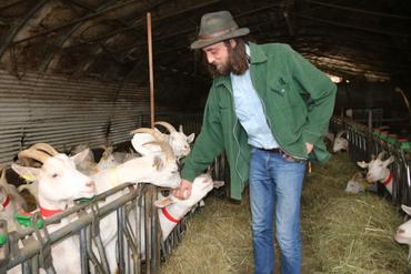 Eleveur tendant la main vers une chèvre blanche