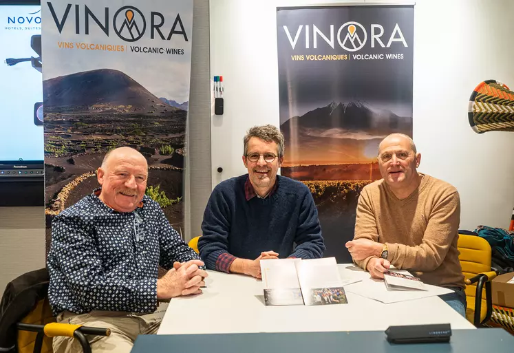 Trois hommes assis devant des kakémonos Vinora.