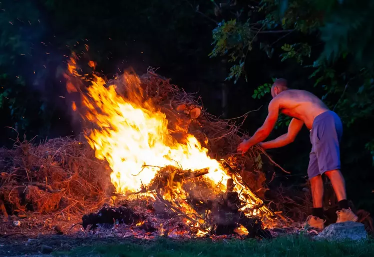 Homme faisant brûler des déchets verts.
