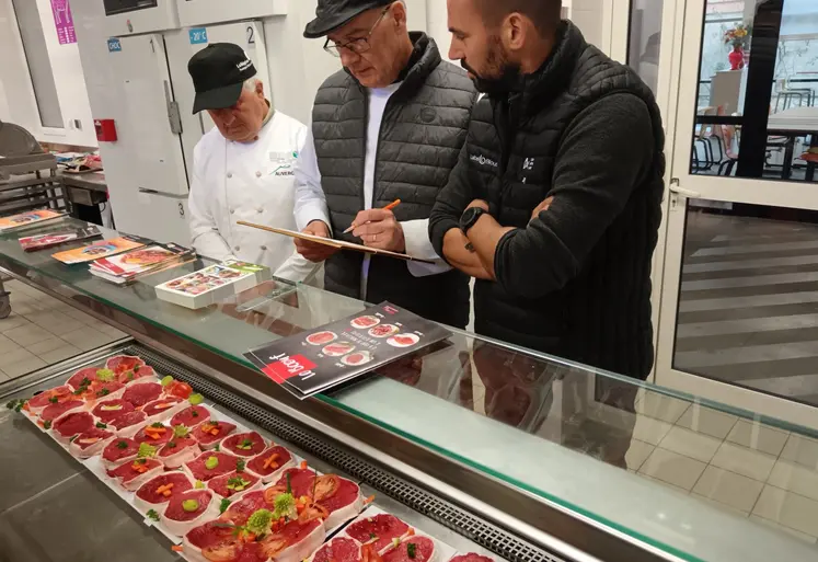 3 hommes observent et jugent des pavés de bœuf découpés par des apprentis bouchers.