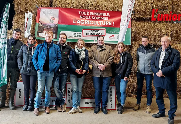 Un groupe d'agriculteurs pose devant des ballots de paille dans un grange de montagne.