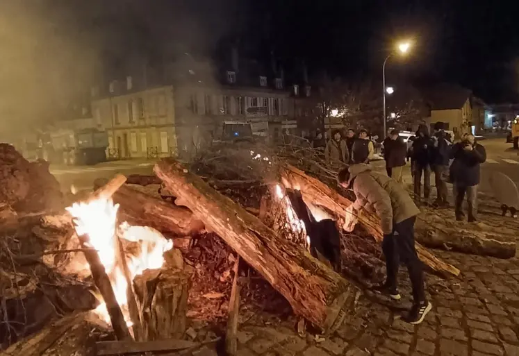 Des agriculteurs allument un feu avec des troncs d'arbres au rond-point Régemortes à Moulins.