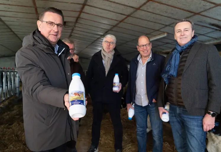 Quatre homme dans une étable, avec une bouteille de lait dans la main.