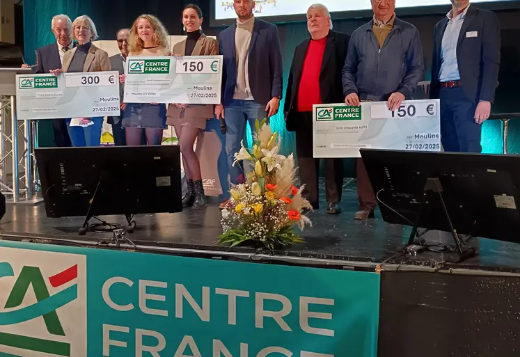 des gens sur un podium posent avec un chèque en main