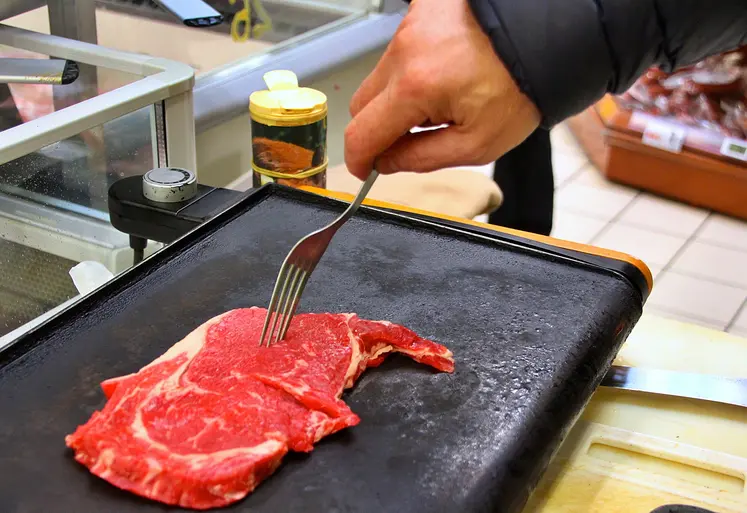 une pièce de boeuf sur une plancha, prête à être retournée à la fourchette