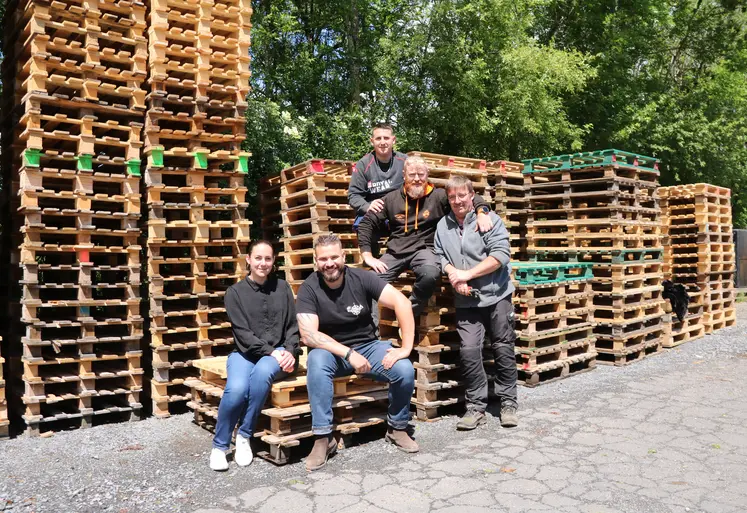 Cinq personnes posant devant des piles de palettes en bois.