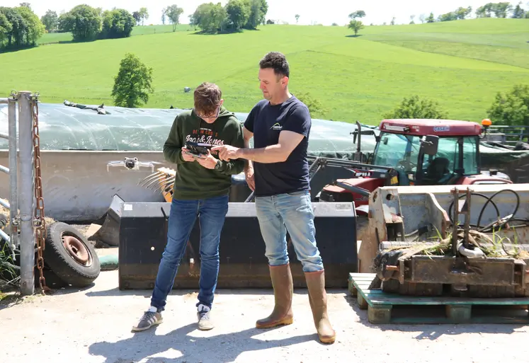 Deux hommes devant un silo de ferme faisant décoller un drone