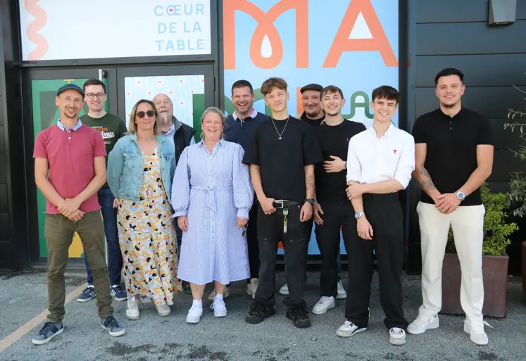 Onze personnes hommes, femmes, posant devant la devanture d'un futur restaurant.