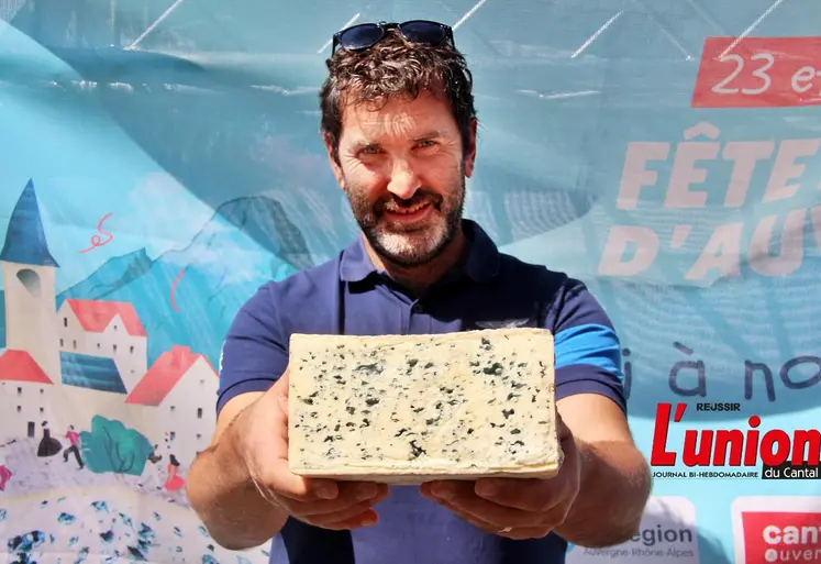 Nicolas Cussac tient dans ses mains une demi fourme de bleu d'Auvergne