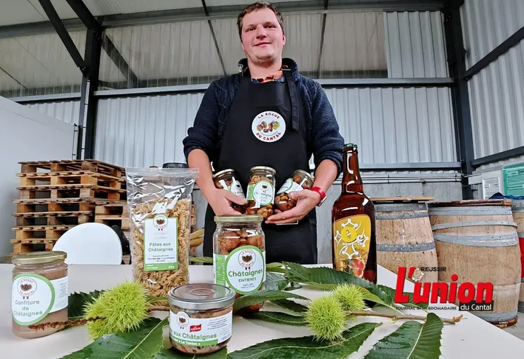 Un homme en tablier noir présente une gamme de produits transformés à base de châtaignes.