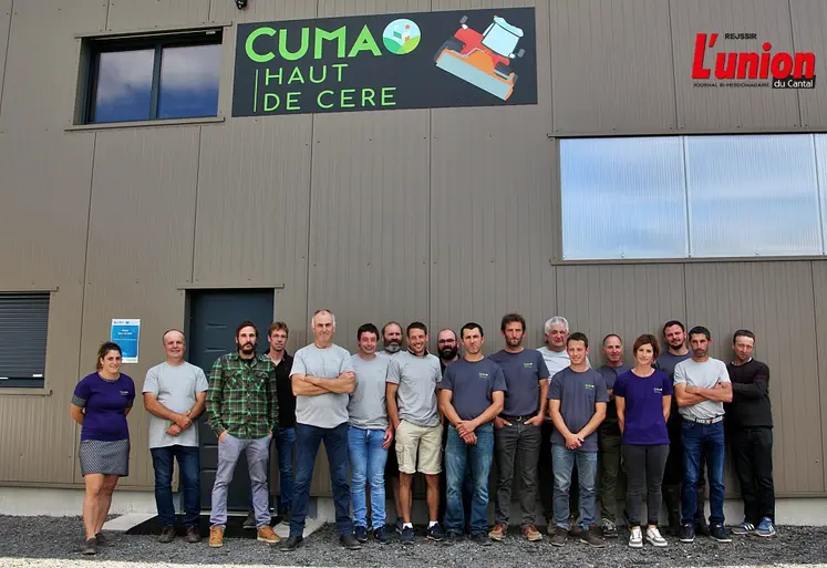 un groupe d'agriculteurs devant le pignon d'un bâtiment agricole avec le logo d'une Cuma