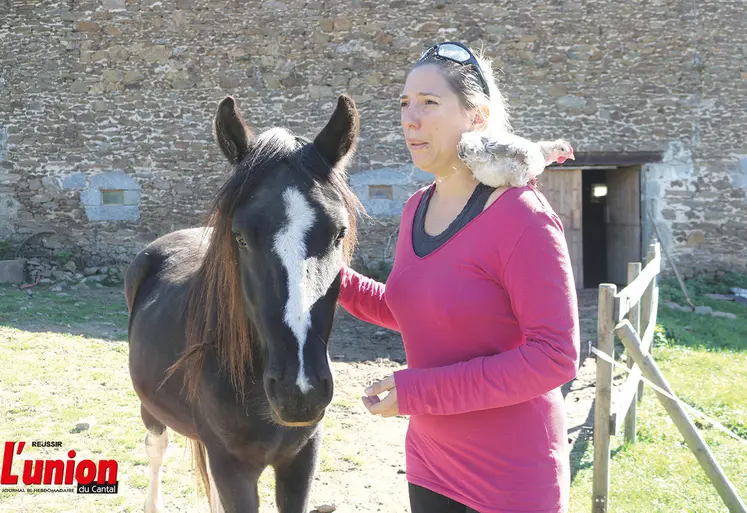 Une dame, à côté d'un cheval et avec un coq sur les épaules