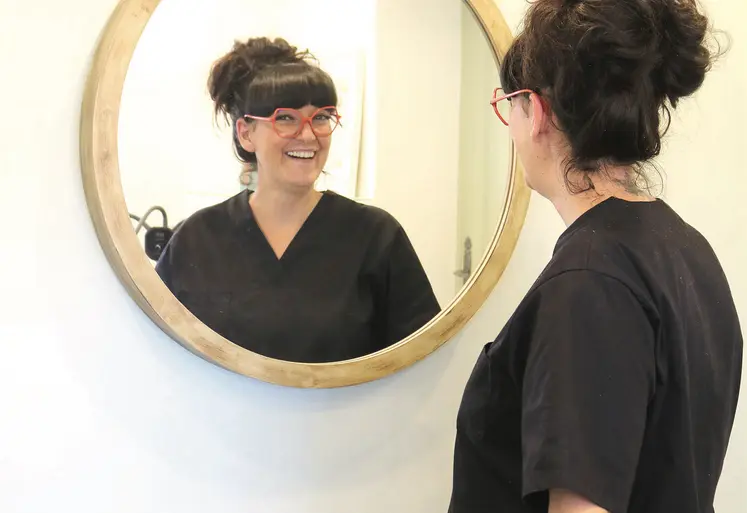 Une dame souriante face à un miroir.