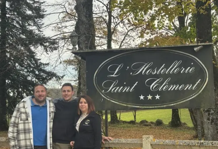 Deux hommes et une femme devant le panneau de l'hostellerie