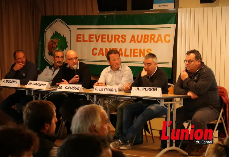 Des personnes assises derreière une table.